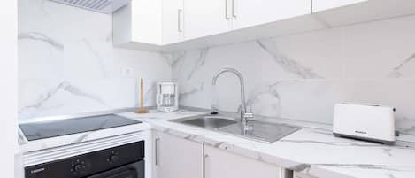 A modern kitchen with white cabinetry, a built-in oven, a coffee maker, and a dishwasher.
