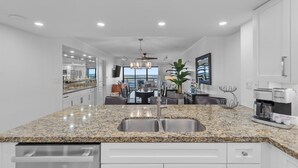 A modern kitchen with granite countertops, stainless steel sink, and a Keurig coffee maker.