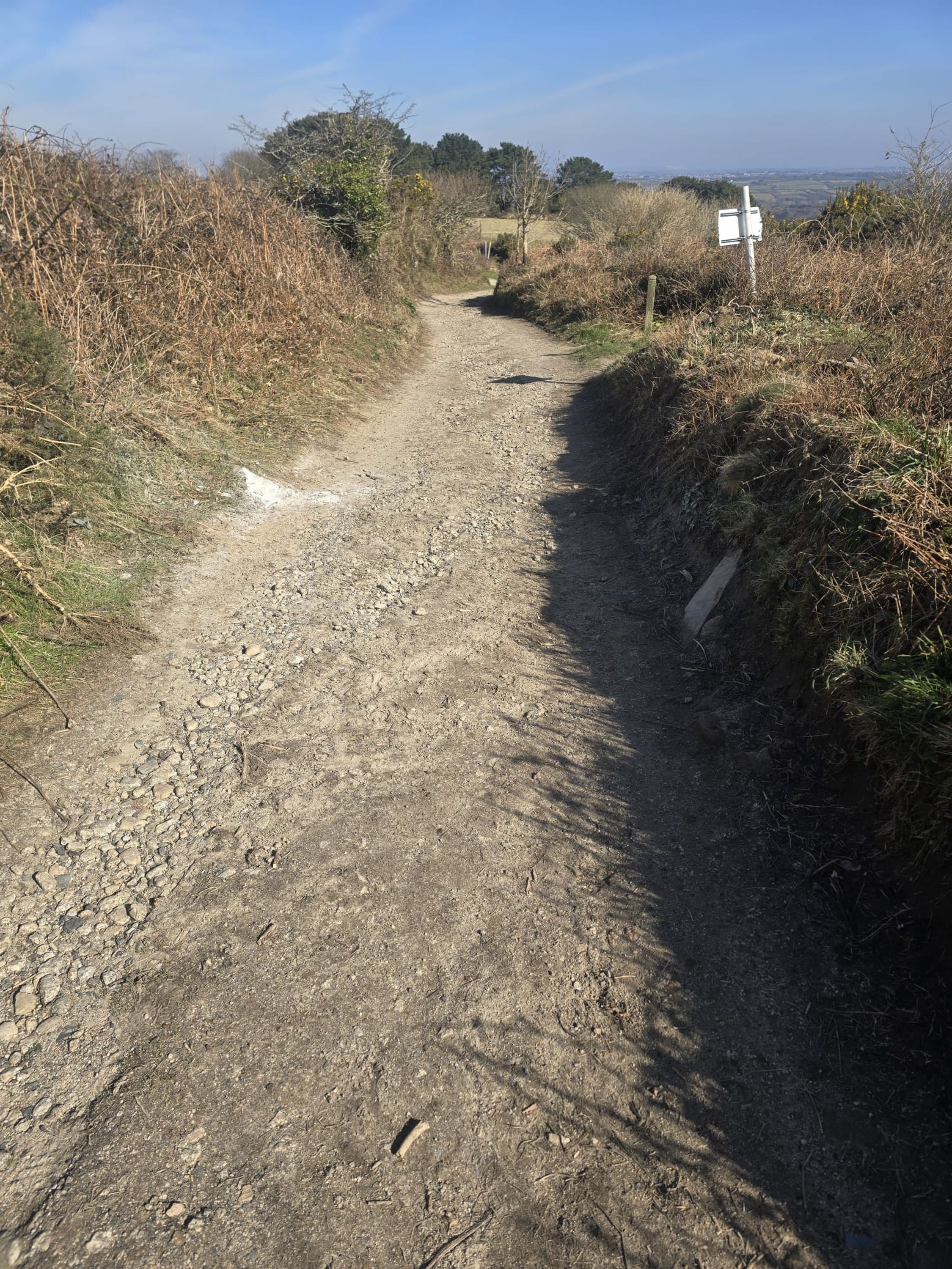 A gravel path with a signpost in a rural setting.