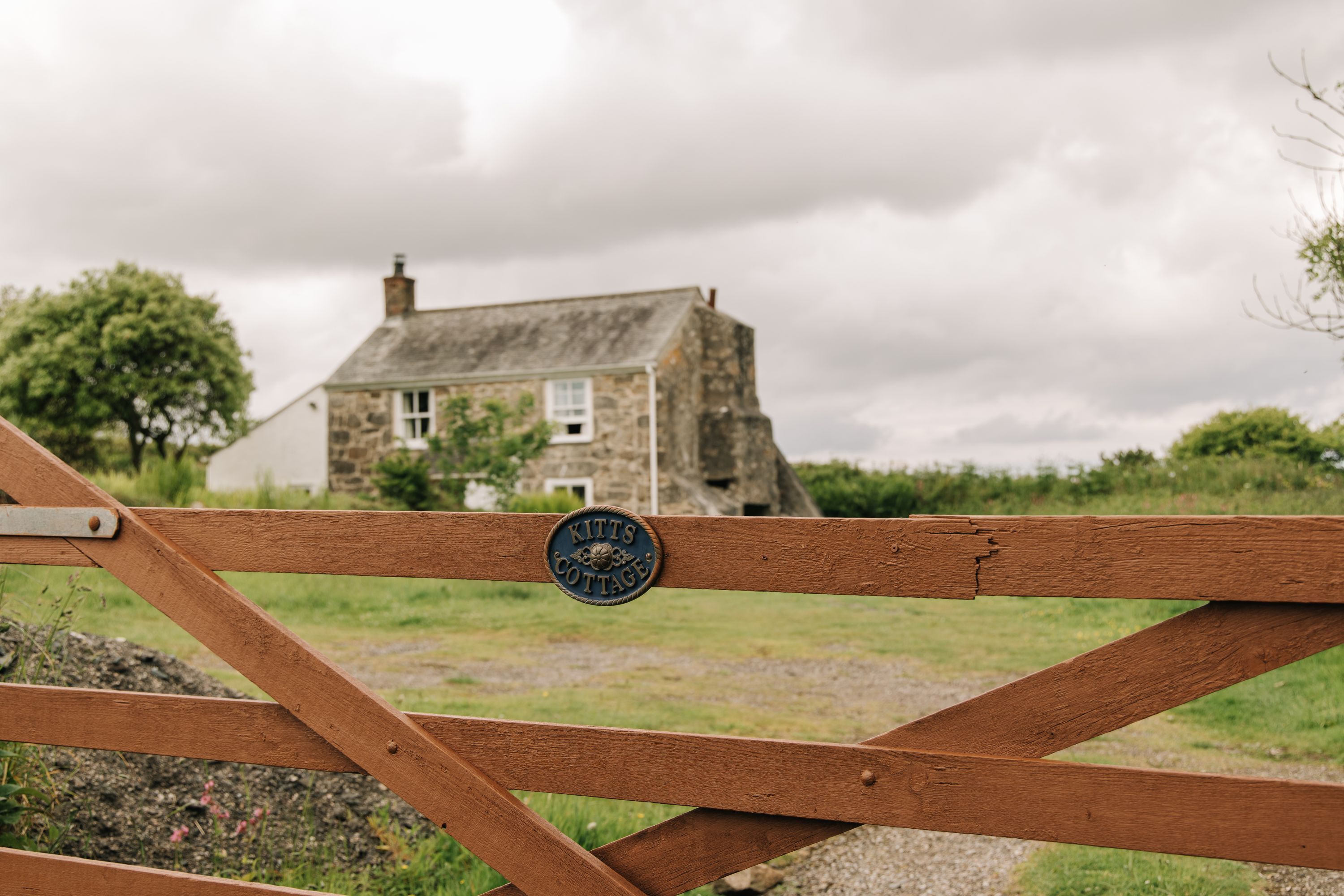 Una verja de madera con un cartel que dice "Kitts Cottage".