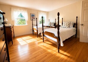 A bedroom with two wooden four-poster beds, a dresser, and a window with curtains. - Waterfront Home With Dock and Two Water Facing Decks! (2372) (Chatham)