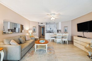 Sala de estar com sofá, mesa de centro, televisão e canto de jantar com cadeiras e mesa.
