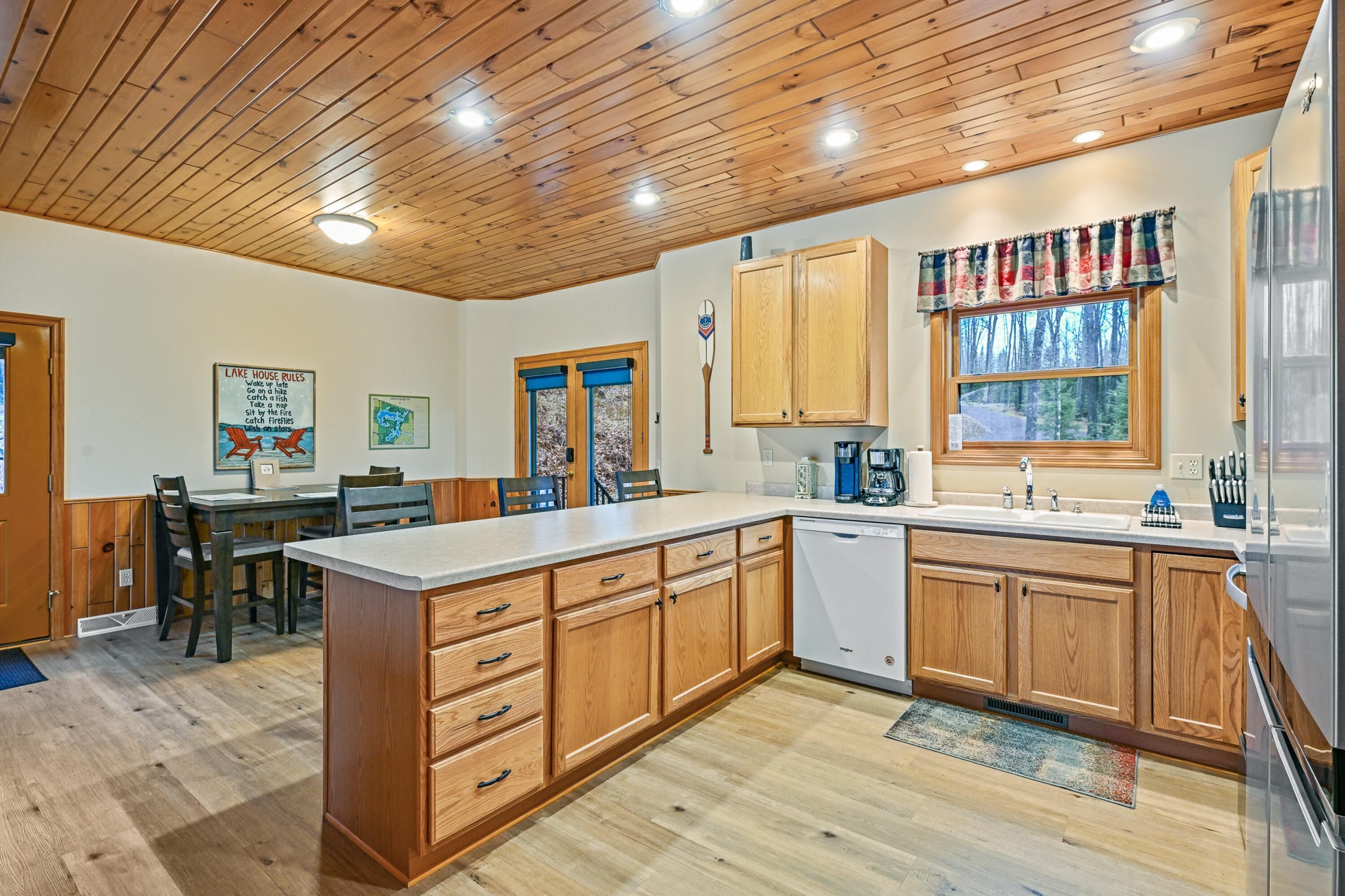Una cocina moderna con armarios de madera, una isla central y un comedor con sillas.