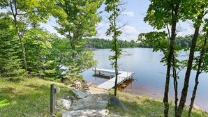 A dock extending into a calm lake surrounded by trees. - Lakeside Haus in Presque Isle (Presque Isle)