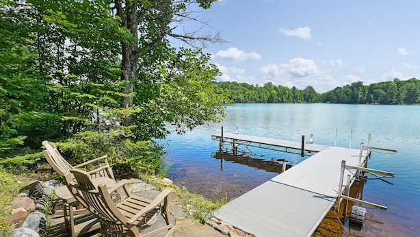 A wooden dock extending into a calm lake, surrounded by lush greenery and trees. - Lakeside Haus in Presque Isle (Presque Isle)