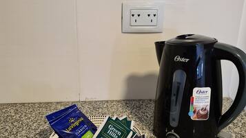 Eine Küche mit einer schwarzen Oster-Kaffeemaschine und einer Kaffeekapseln-Platte.