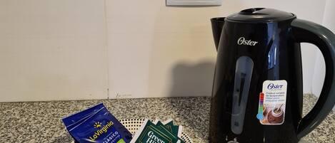 Una cocina con una cafetera Oster negra y un plato de cápsulas de café.