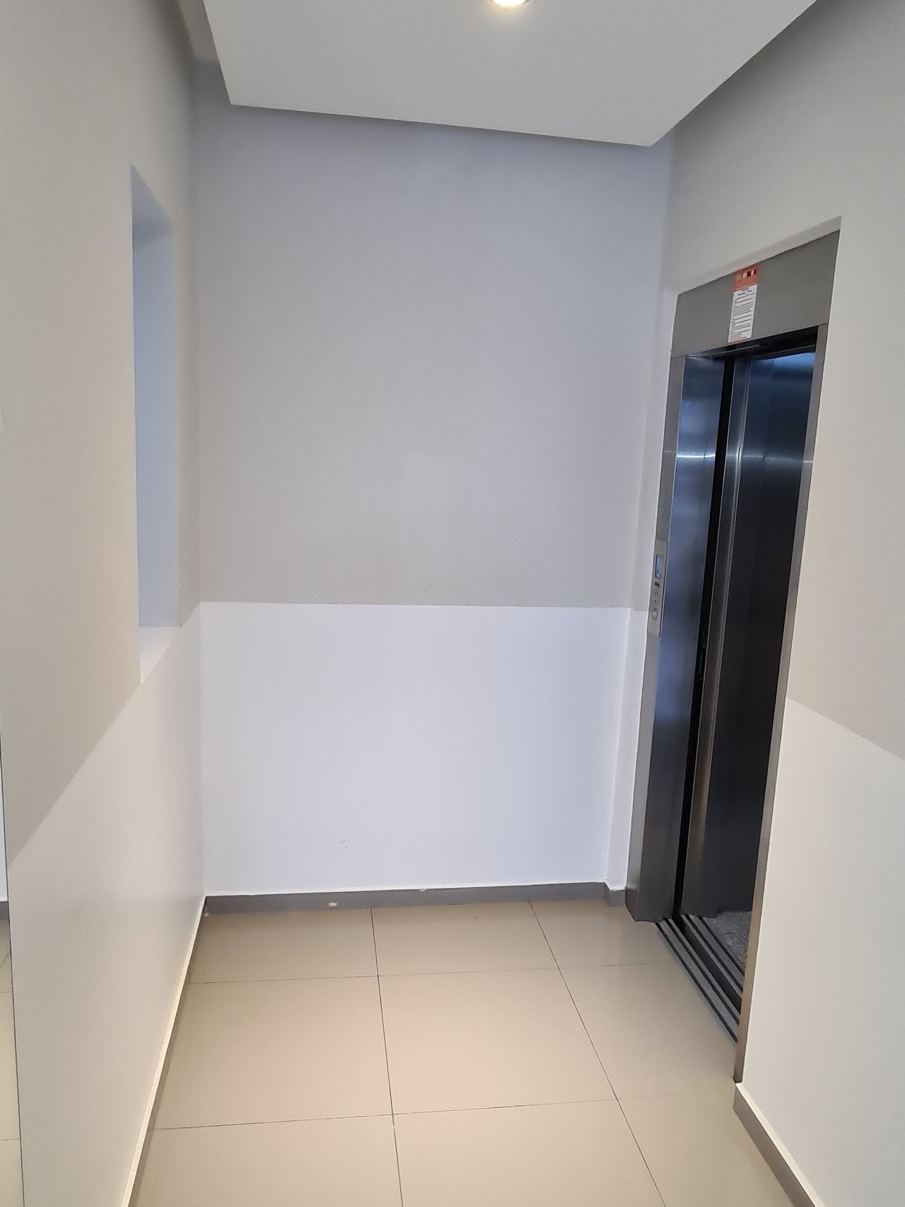 A hallway with a tiled floor, white walls, and a closed elevator door.
