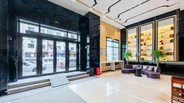 A hotel lobby with a glass entrance, seating area, and a bookshelf.