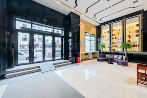 A hotel lobby with a glass entrance, seating area, and a bookshelf. - Lifeng Hotel (Gogol Street, Harbin Railway Station) (Harbin)