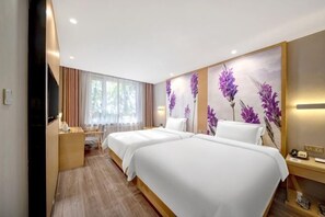 A hotel room with two beds, a desk, a TV, and a large window with curtains.