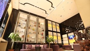 A modern lobby with a central seating area, a large bookshelf, and decorative wall panels.