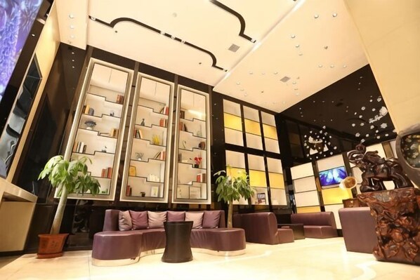 A modern lobby with a reception desk, seating area, and decorative shelves.
