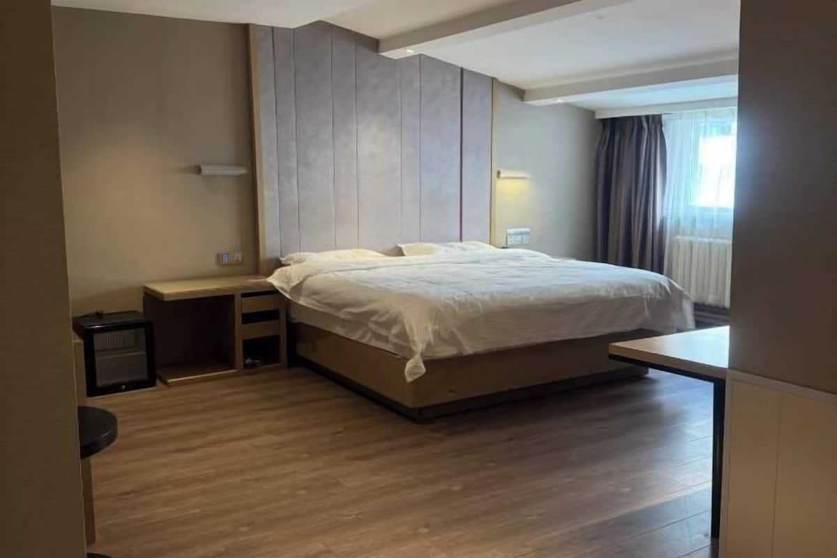Un dormitorio moderno con cama, mesitas de noche y una ventana con cortinas.