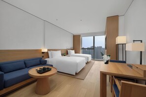 Ein modernes Hotelzimmer mit einem großen Bett, einer Sitzecke, einem Schreibtisch und Blick auf die Stadt.