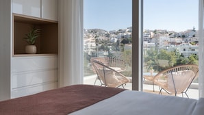 A bedroom with a large window, a bed, a bedside table, and two wicker chairs. - Athenian Riviera Elegant Residence (Vari-Voula-Vouliagmeni)