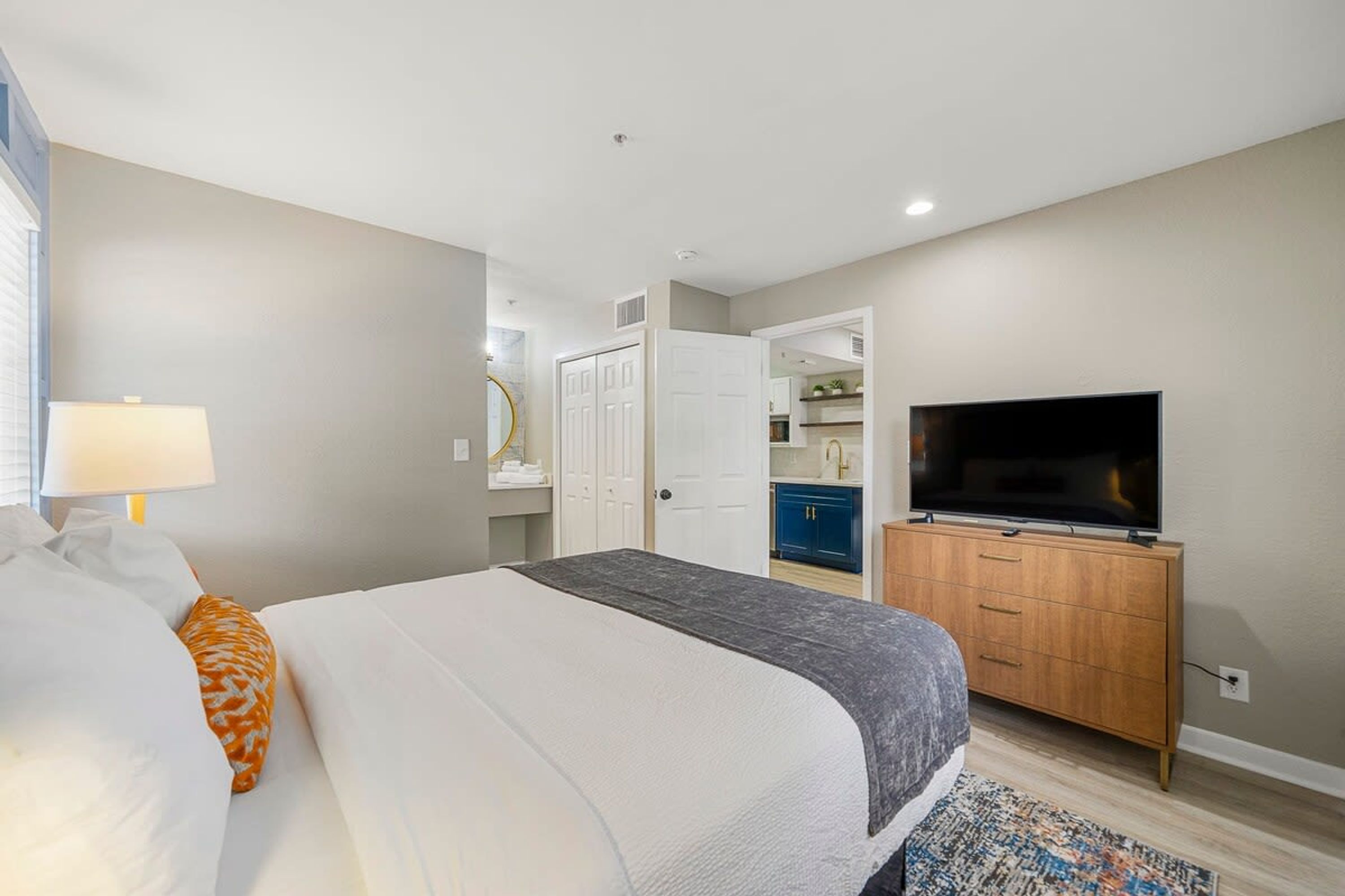 Une chambre d’hôtel avec un lit, une télévision, une armoire et une salle de bain visible à travers une porte ouverte.