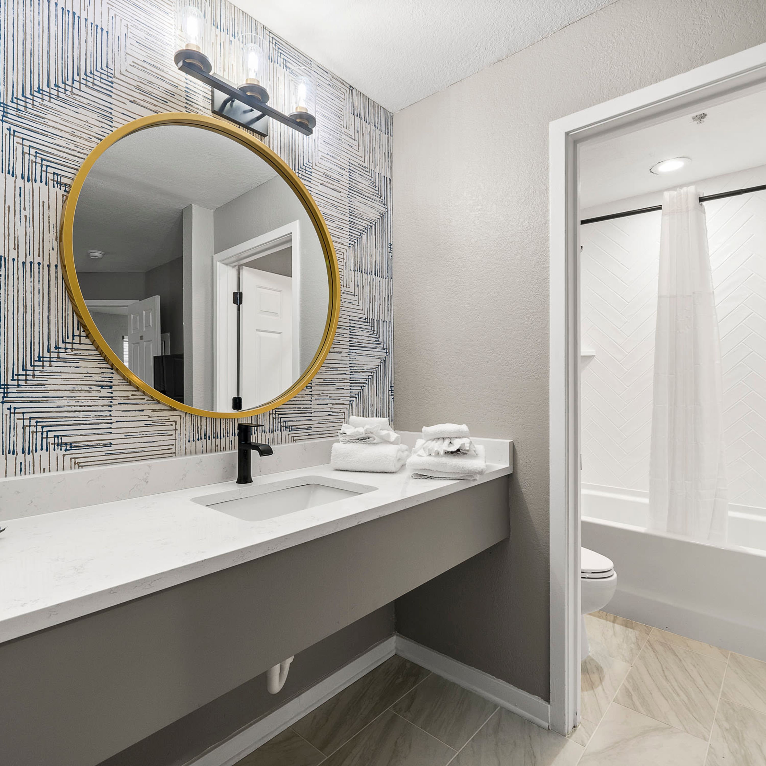 Une salle de bain avec un grand miroir, un lavabo et une douche.