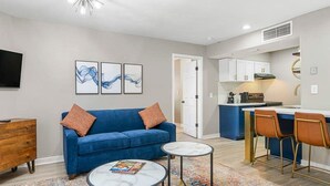 Un salon moderne avec un canapé bleu, deux tables basses et un tapis coloré.