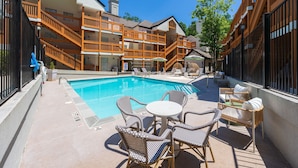 A pool area with lounge chairs and a table, surrounded by wooden buildings with balconies. - Newly Renovated Atlanta Gem Central Buckhead Apt (Atlanta)