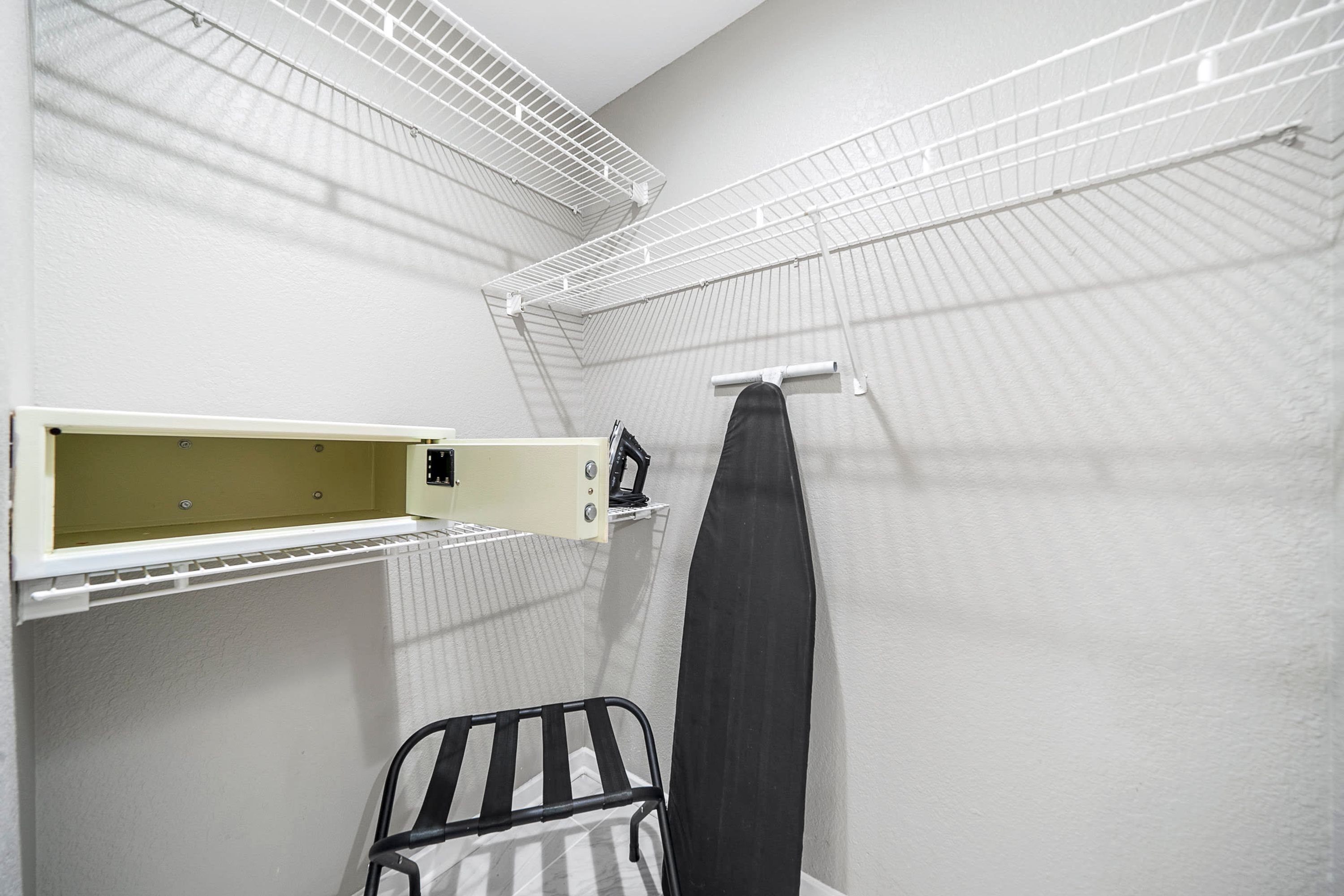 A small, enclosed room with a radiator, a shelf, and a hanging garment.