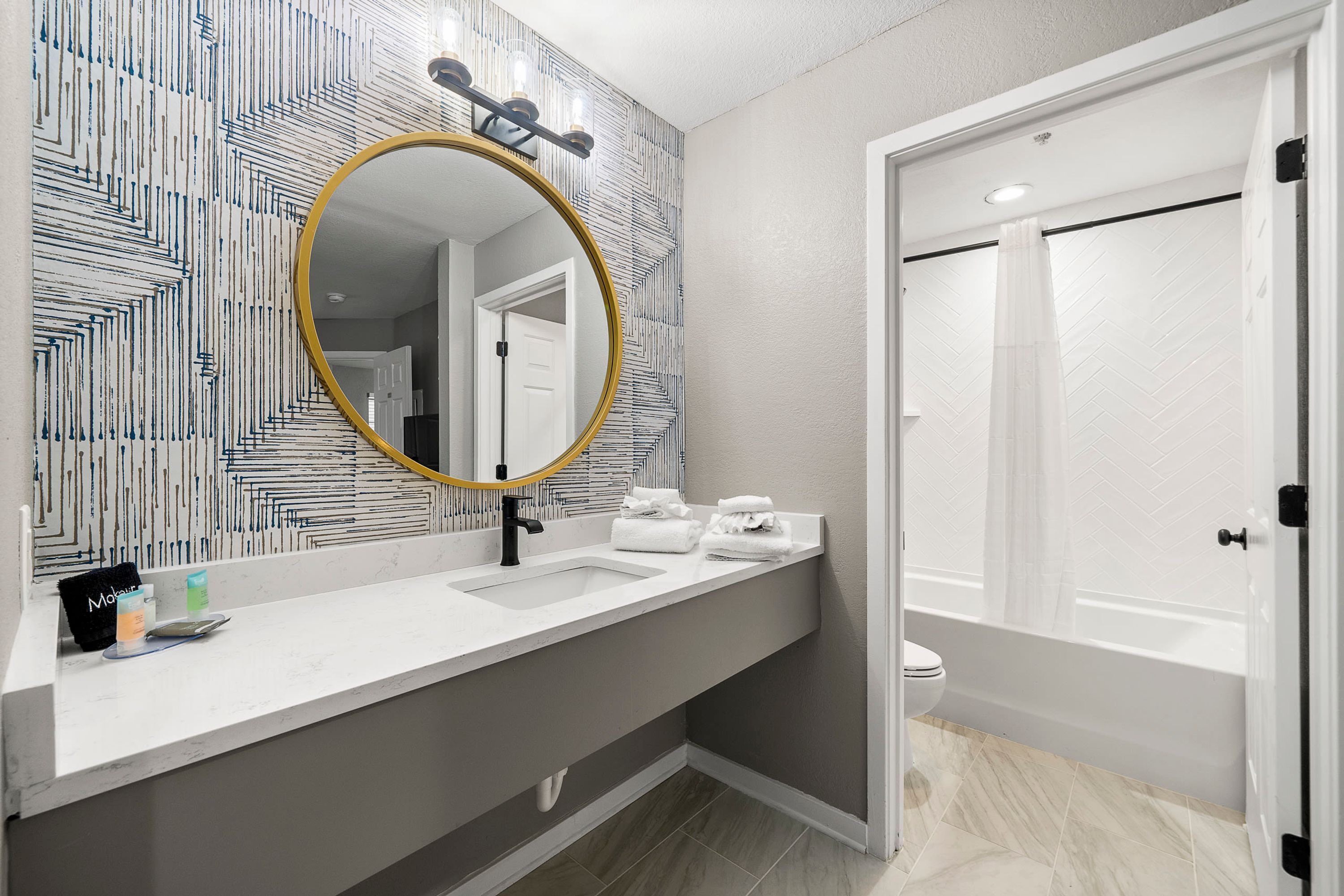 A bathroom with a large mirror, two sinks, a toilet, and a shower.