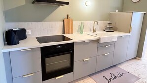 Una cocina moderna con horno negro, estufa integrada, lavaplatos y tabla de cortar de madera.