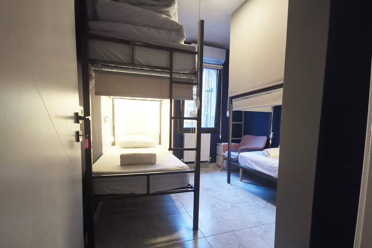 Ein Schlafsaalzimmer mit Etagenbetten, einem Fenster mit Vorhängen, einem Schreibtisch und einem Stuhl.
