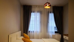 A hotel room with a bed, a bedside lamp, and a window with curtains. - Gafa Garden Hostel & Apartments (Istanbul)