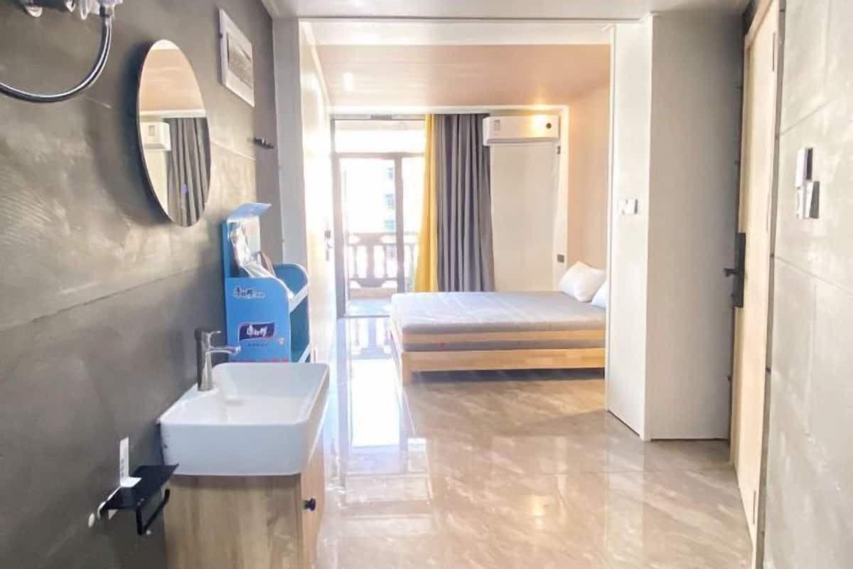 A hotel room with a bathroom, a bed, and a view of the outside.