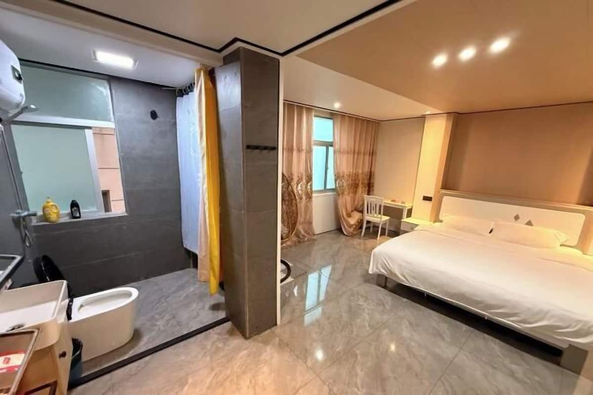A modern hotel room with a large bed, a separate bathroom, and a small desk area.