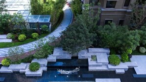 A landscaped area with a water feature, stone planters, and a curved pathway.
