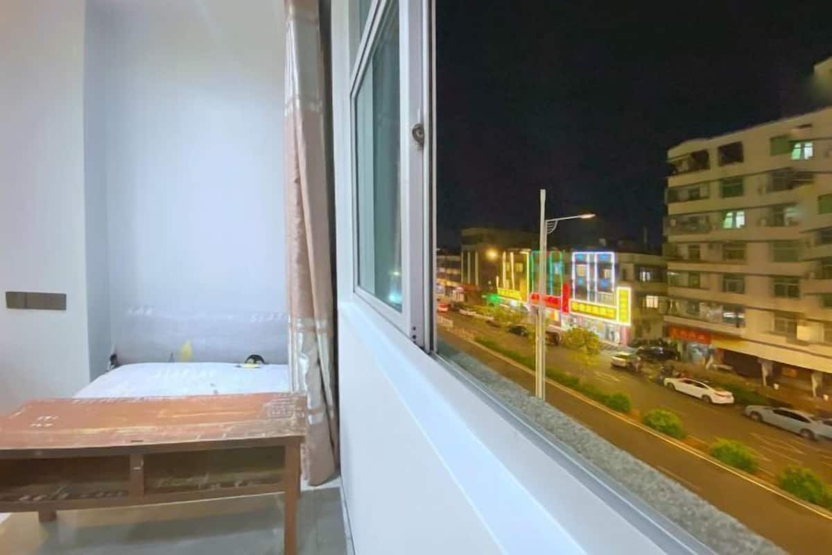 A room with a window overlooking a street at night.