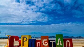 Colorful letters spelling 'TOPPING' on a beach with a clear sky.