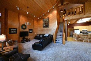 A log cabin interior with a living room, a staircase to a loft, and a kitchen area. - Secluded Mountain Cabin 30 Min to Yellowstone (Island Park)
