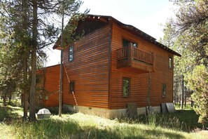A log cabin with a balcony, surrounded by trees.
