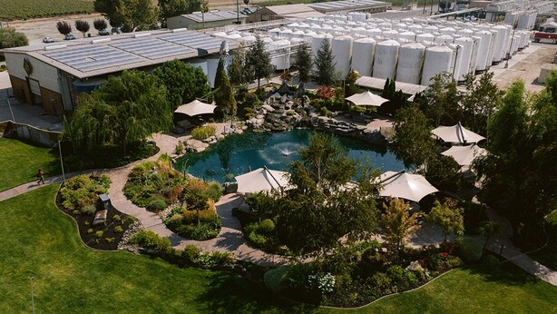 Een groot industrieel complex met meerdere opslagtanks, een zwembad omringd door parasols, en een aangelegde tuin.