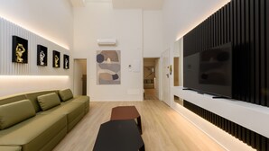 A modern living room with a green sofa, a black coffee table, a flat-screen TV, and artwork on the walls. - Anguillara Full Design by Mmega (Florence)
