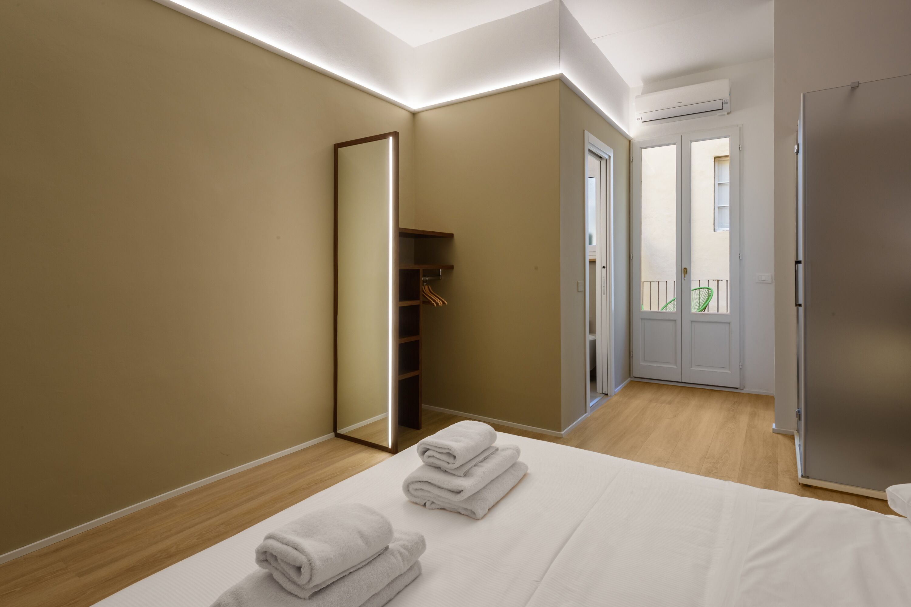 A modern bedroom with a large bed, a wardrobe, and a walk-in closet.