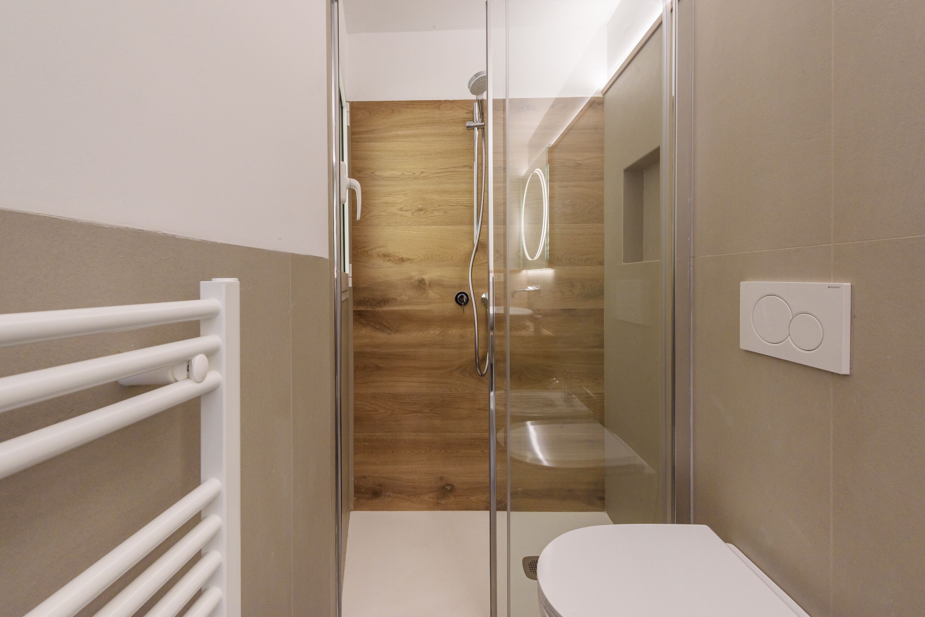 Une salle de bain moderne avec une douche à parois de verre, des toilettes blanches et un meuble-lavabo en bois.