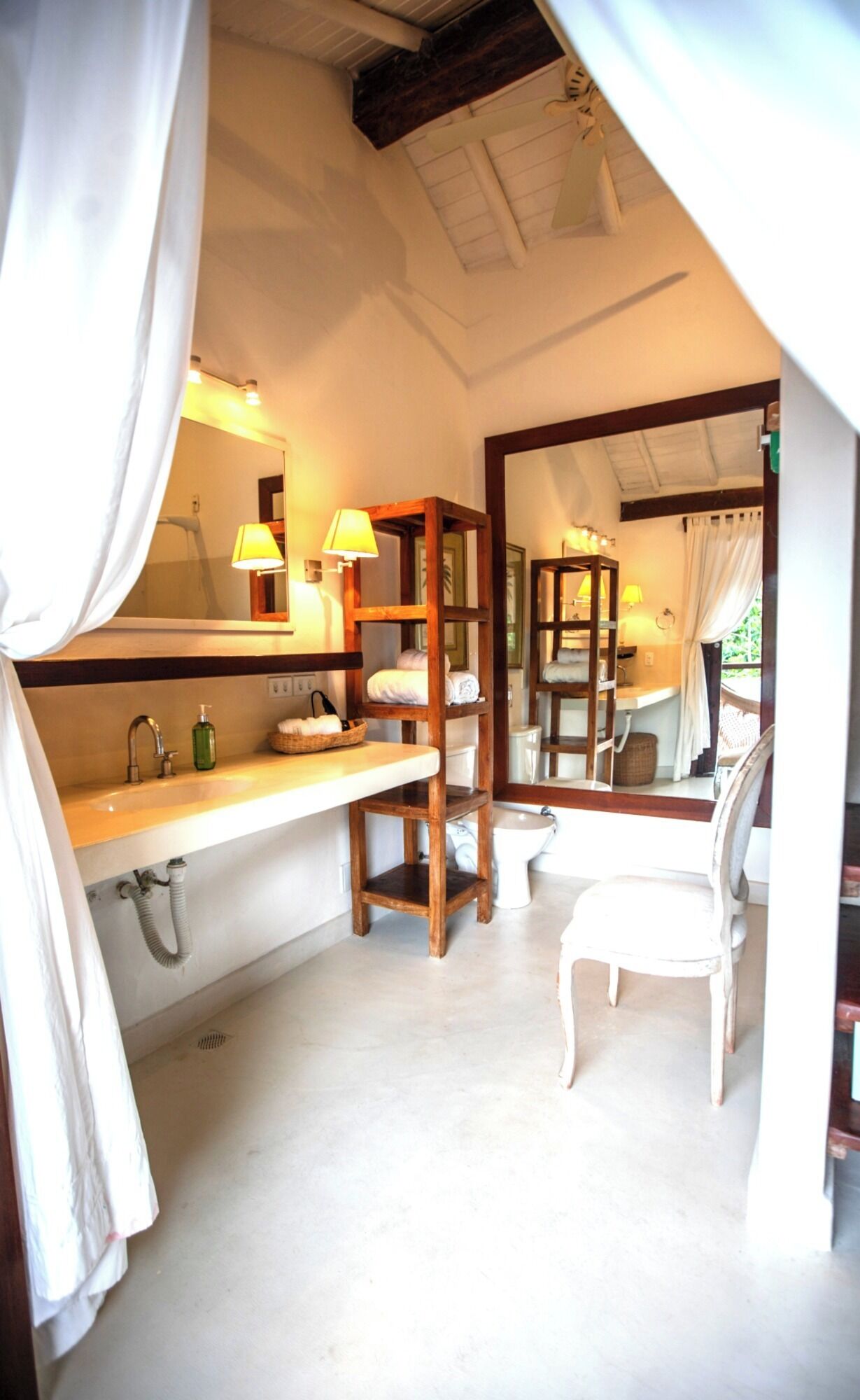 A bathroom with a wooden shelf, a chair, a sink, and a mirror.