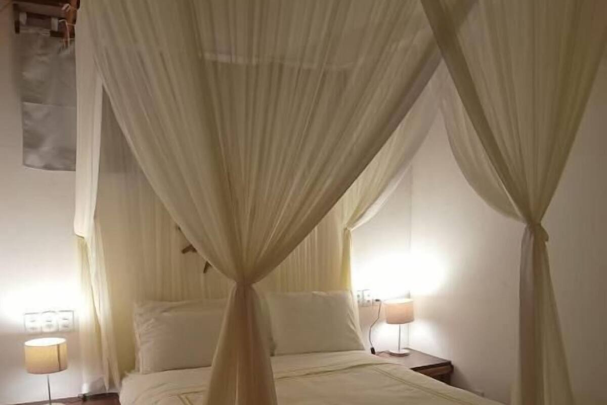 A bedroom with a bed, two bedside tables, and a canopy bedspread.