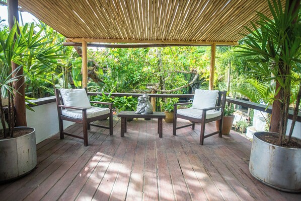 A covered outdoor seating area with wooden furniture and potted plants. - Monkey Casa Hotel (Porto Seguro)