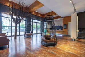 A spacious lobby with a wooden ceiling, large windows, and a central seating area with a tree sculpture and a black metal spiral structure. - Tuke Global Hotel (Wenzhou Louqiao South Railway Station) (Wenzhou)