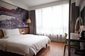 A hotel room with a bed, a desk, a chair, a window with curtains, and a wall with a mural. - Tuke Global Hotel (Wenzhou Louqiao South Railway Station) (Wenzhou)