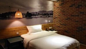 Una habitación de hotel con una cama, una mesita de noche, una lámpara y un mural en la pared.
