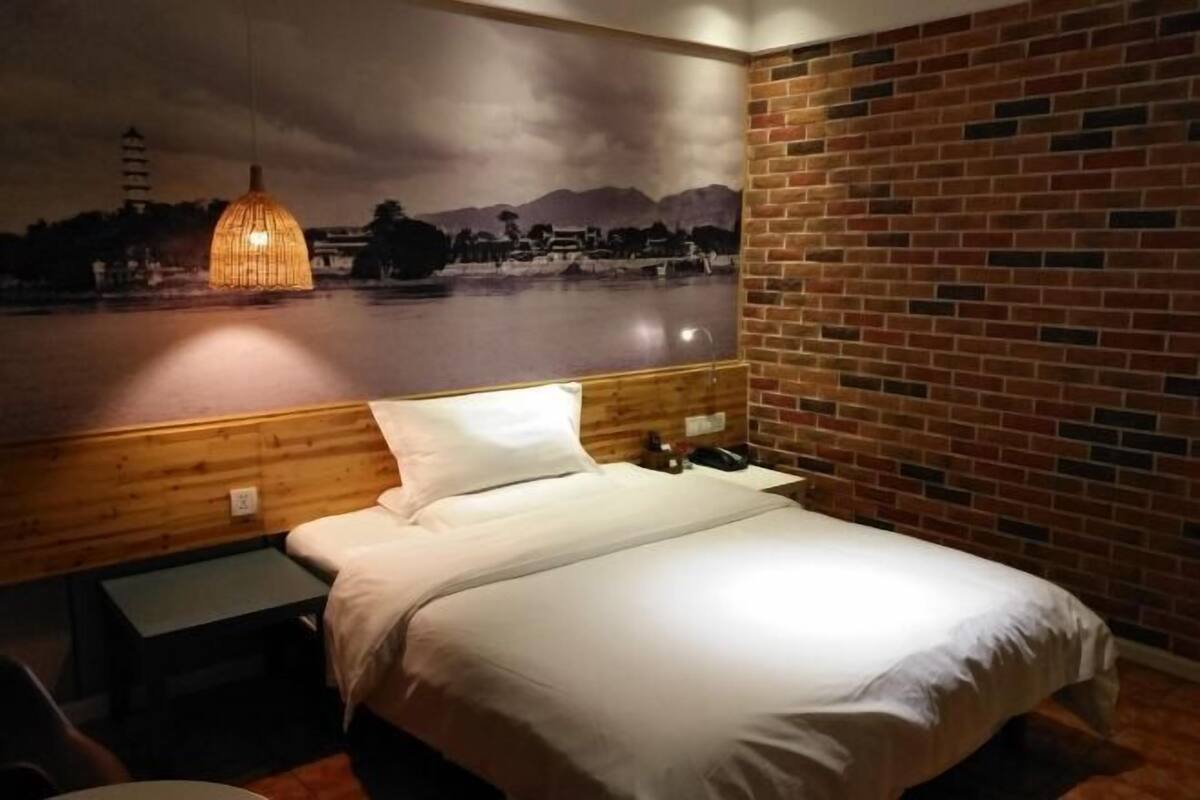 Una habitación de hotel con una cama, una mesita de noche, una lámpara y un mural en la pared.