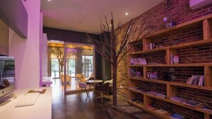 Un interior moderno con una estantería de madera, un escritorio con una computadora y una zona de estar con sillas y una mesa.