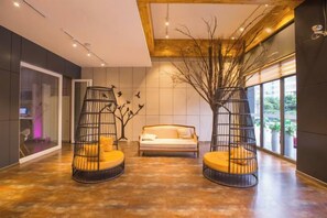 A modern interior with a sofa and two black metal chairs with cushions, a wooden ceiling, and a large window with a view. - Tuke Global Hotel (Wenzhou Louqiao South Railway Station) (Wenzhou)