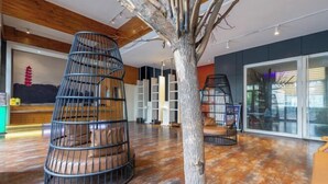 Un interior moderno con techo de madera, una escultura de árbol y dos sillas de metal negro.
